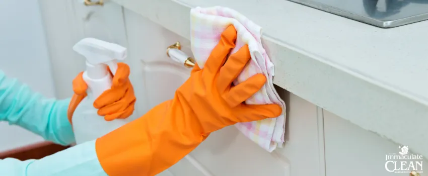 IC - Person wearing orange gloves cleaning counter tops