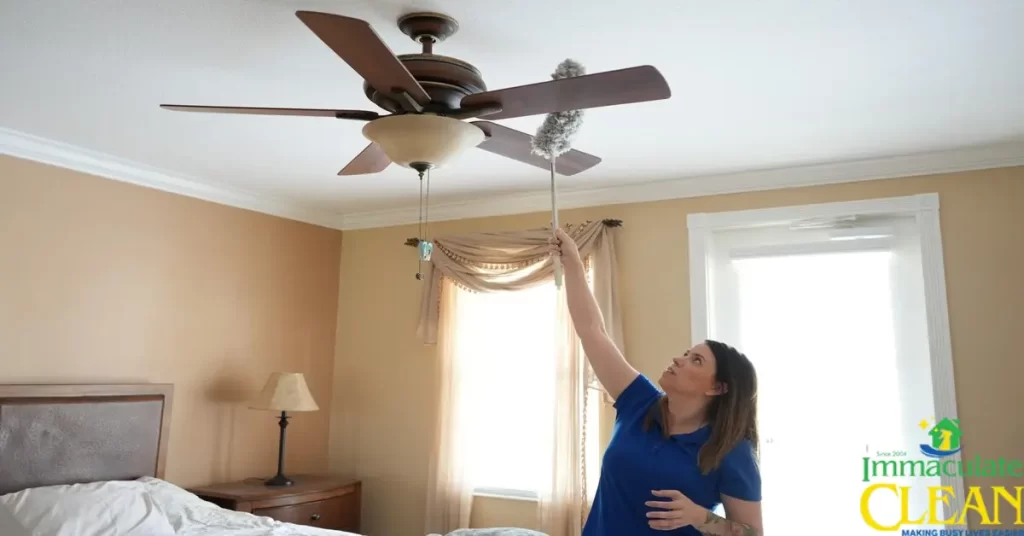 A woman cleaning a ceiling fan in a bedroom | IC